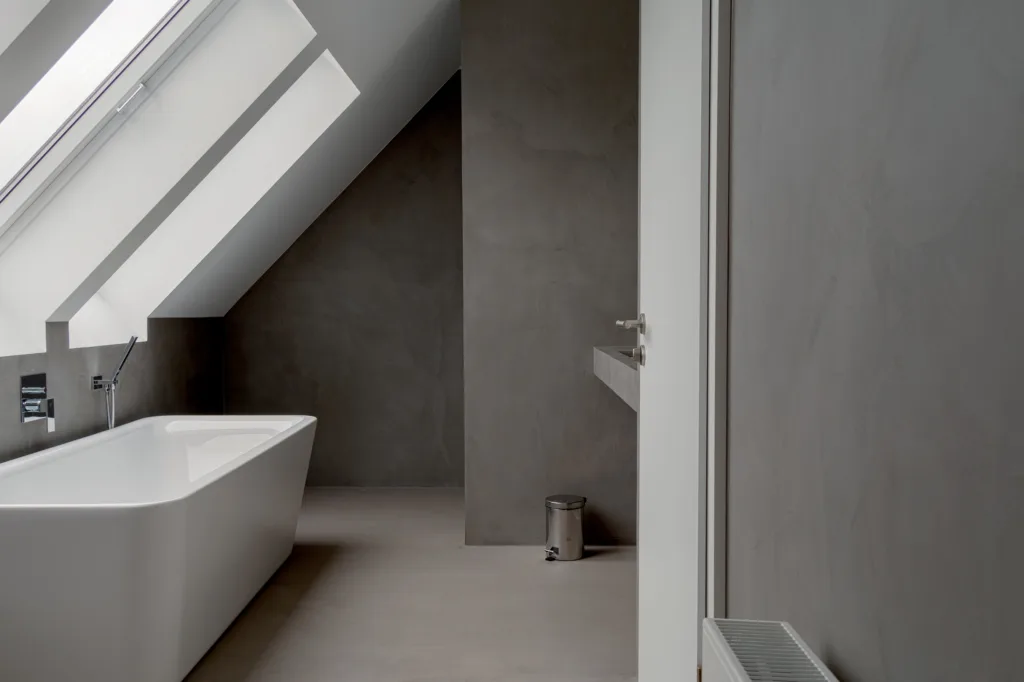Grå mikrosement på vegg og gulv på bad med badekar